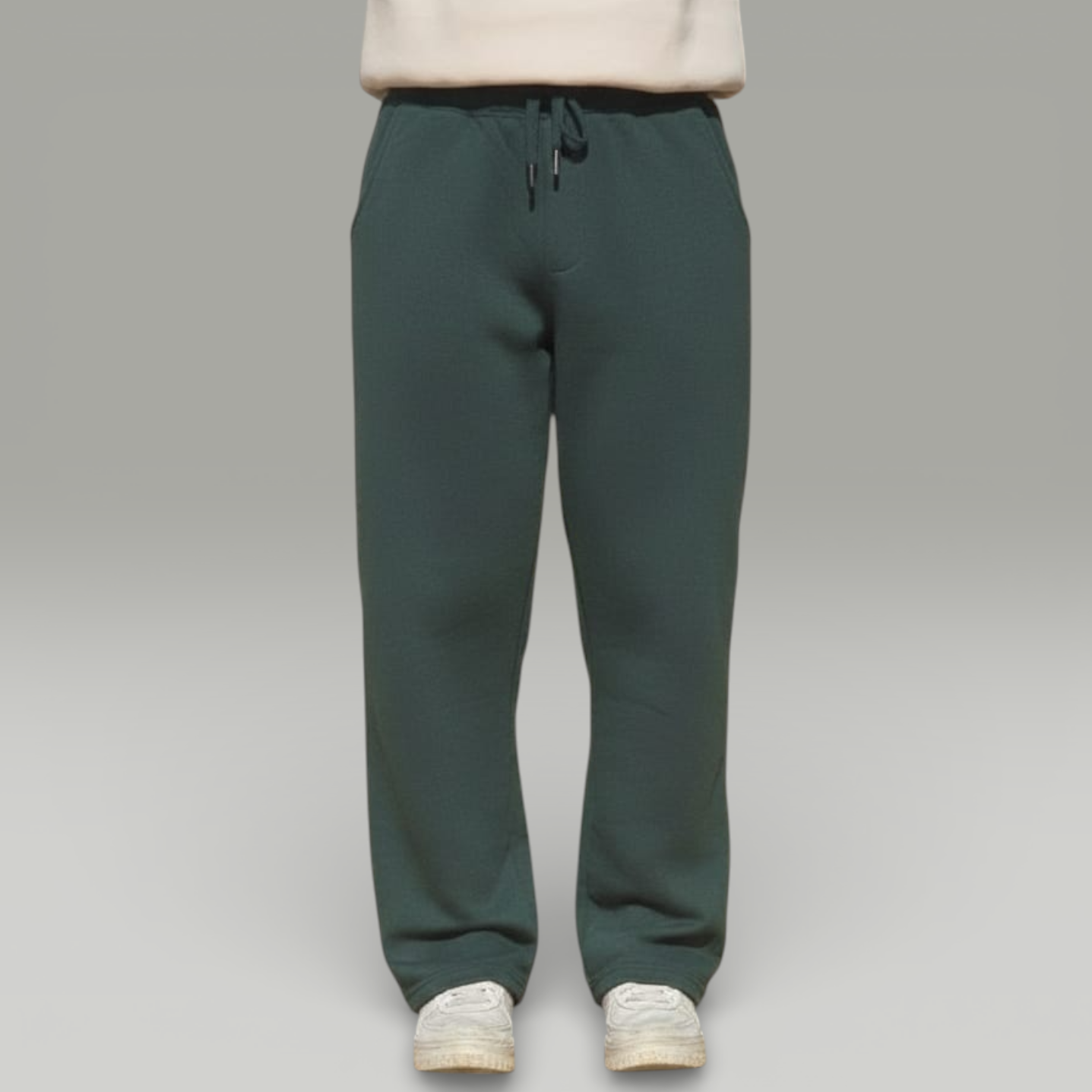 Green sweatpants worn with a beige sweater on a gray background