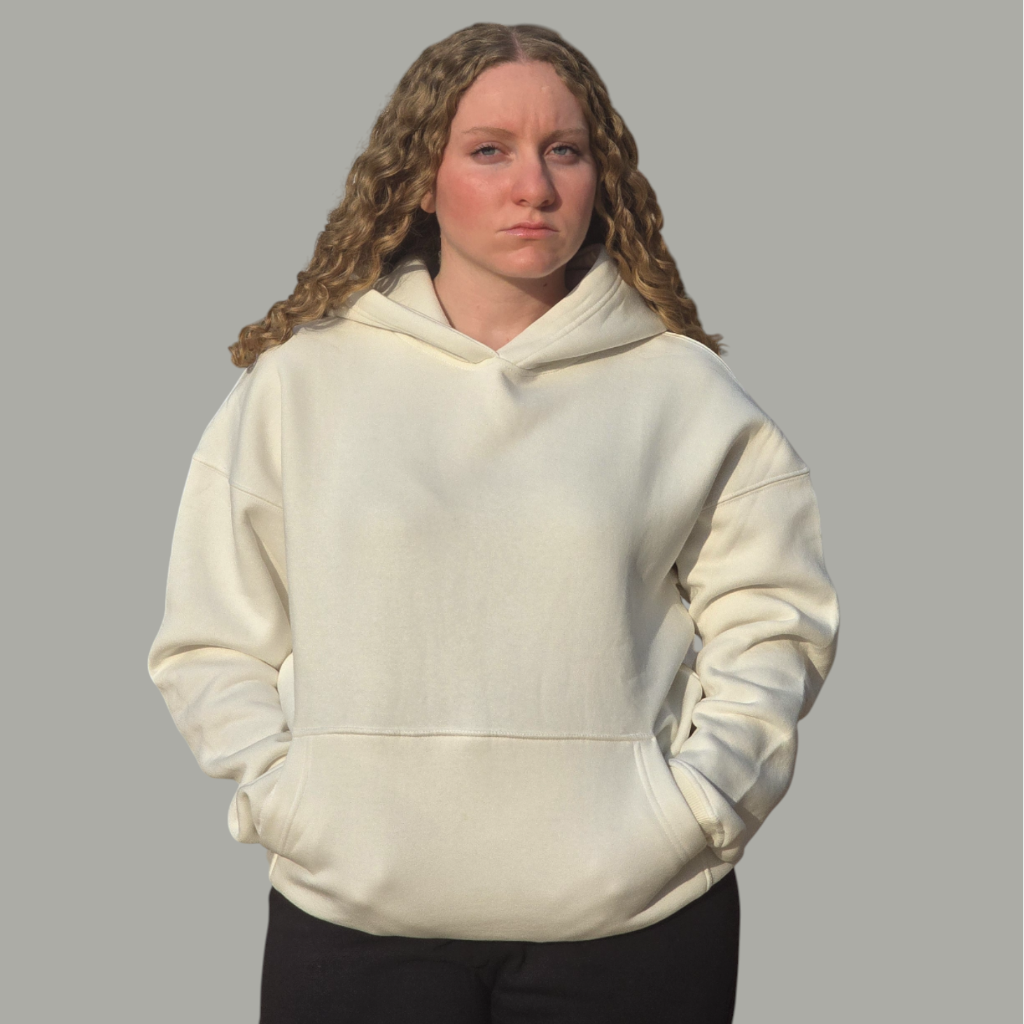 Person wearing a cream hoodie against a gray background