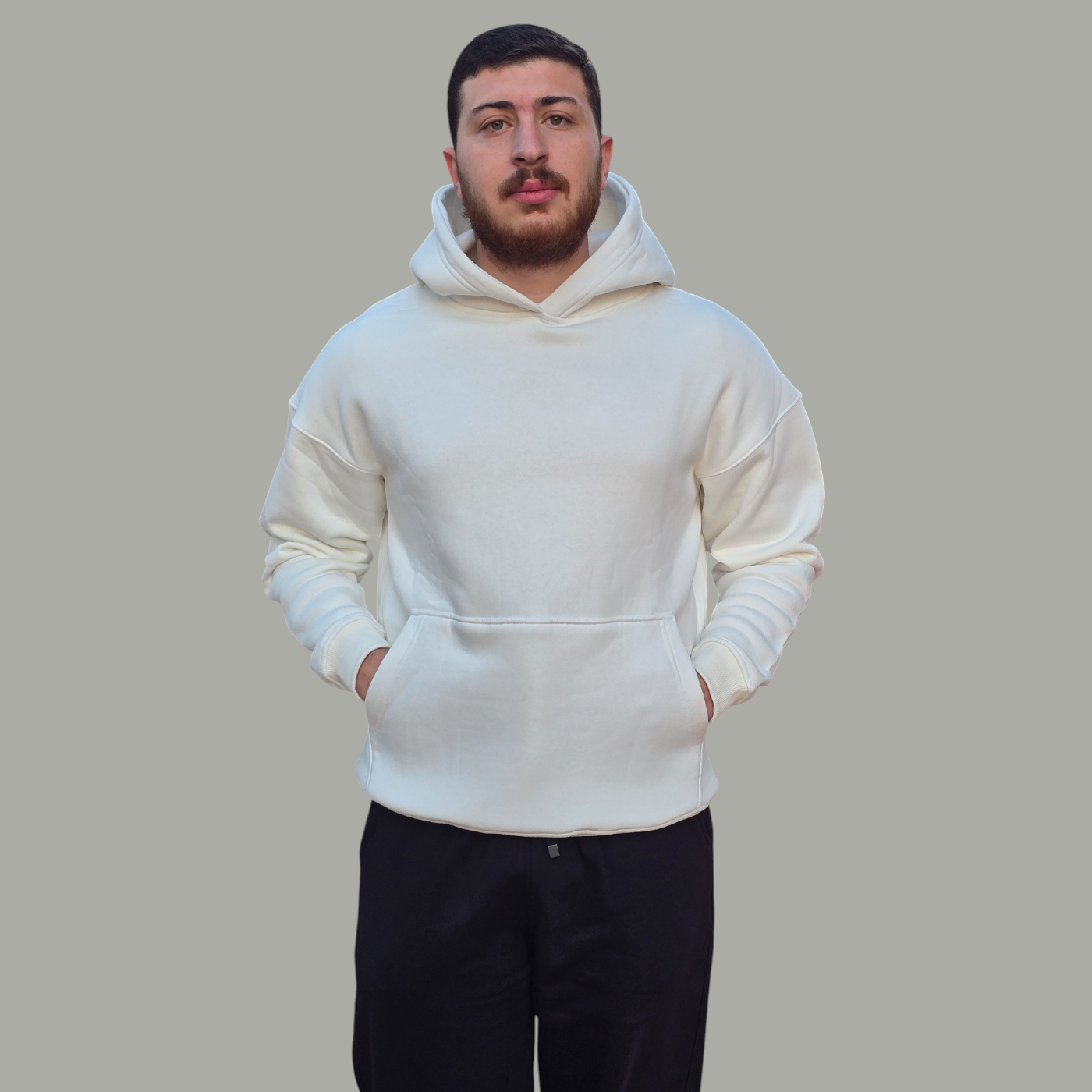 Man wearing a white hoodie and black pants on a gray background