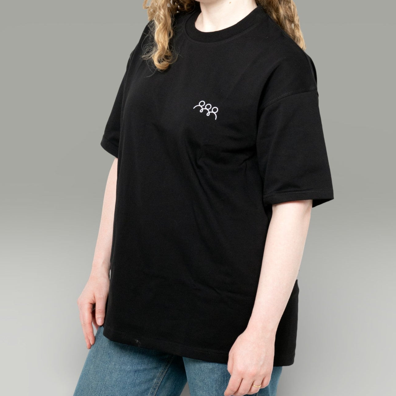 Person wearing a black t-shirt with a logo on a gray background