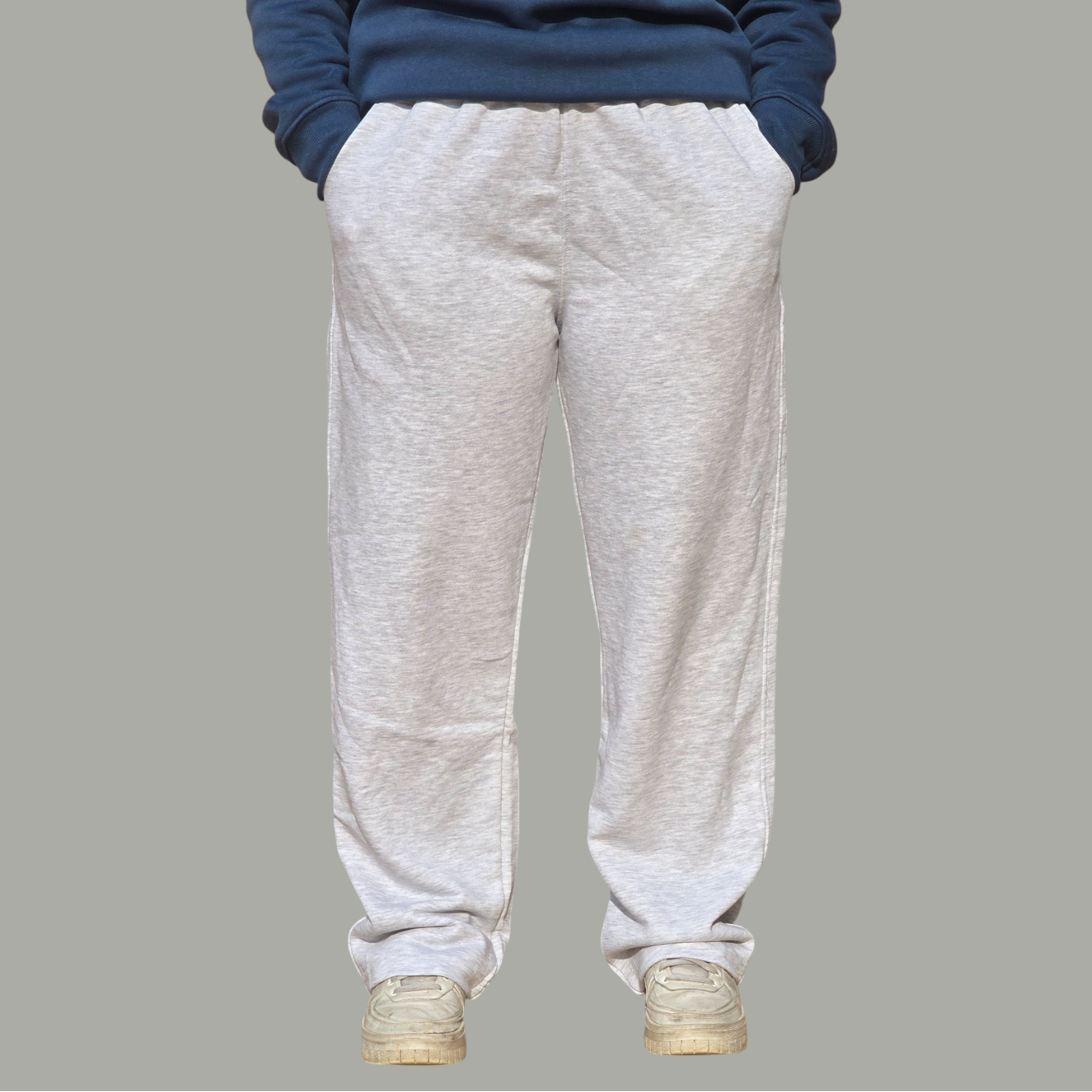 Person wearing a blue sweatshirt and gray sweatpants on a gray background
