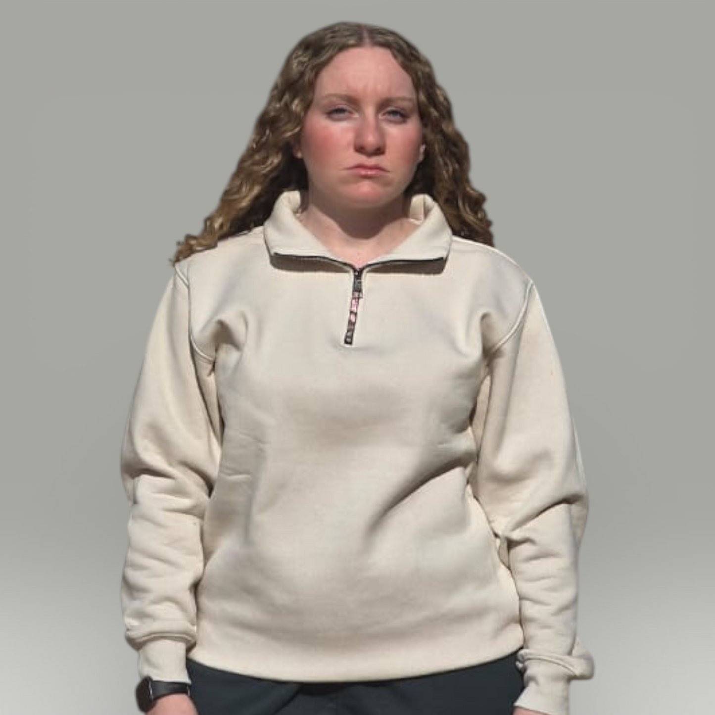 Person wearing a beige fleece pullover with a zipper on a gray background