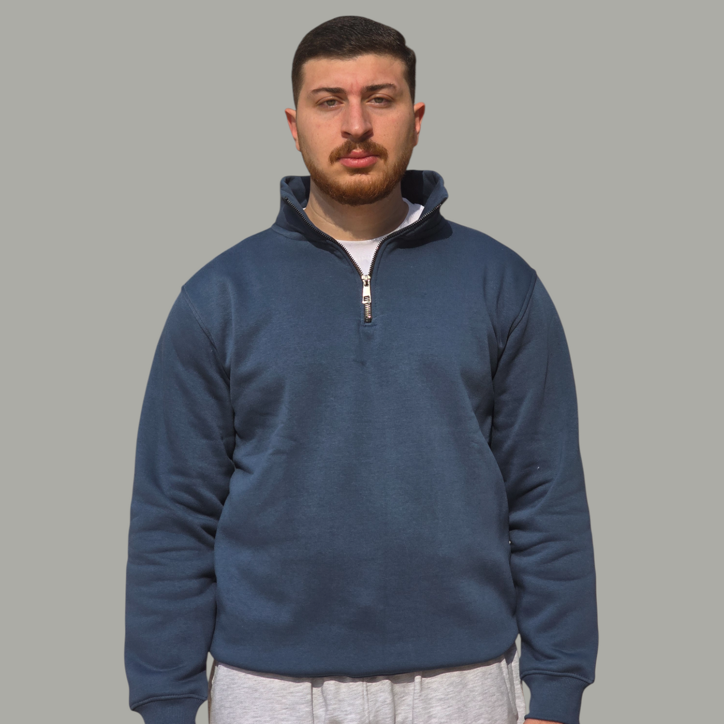 Man wearing a petrol pullover with a zipper on a gray background