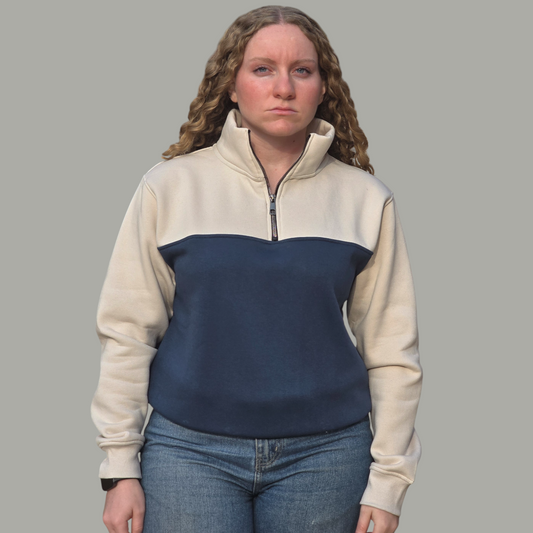 Person wearing a two-tone pullover with beige and navy colors on a gray background