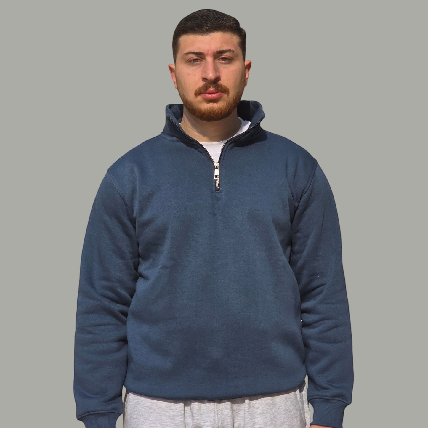 A man wearing an AnyWear unisex blue quarter-zip pullover sweatshirt with a stand-up collar and metal zipper.